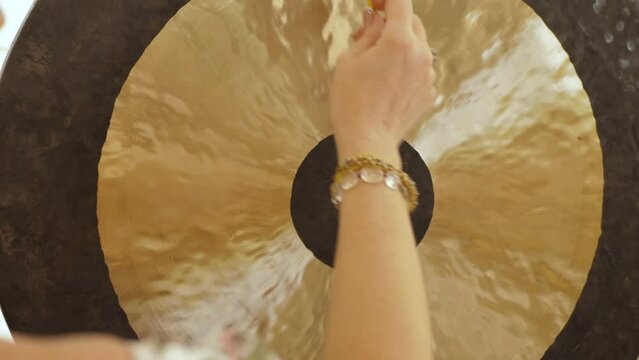 Little gong hammer and Gong, close-up. Women's hands make the sound of a gong with small soft mallet
