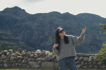 Woman taking a selfie in a mountain landscape in the Andes mountains (South America) enjoying her vacation. Concept professions, people, travels and vacations.