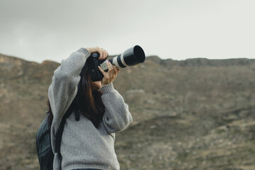 Woman photographer taking pictures with her camera in a part of the Andes mountain range in Peru. Concept professions, people, travels and vacations.