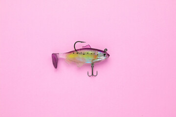 Silicone bait for fish in the shape of a fish, pink hook on a background, flat lay
