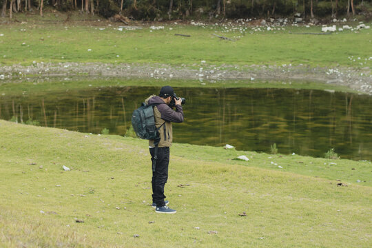 Photographer taking pictures with his camera in a green valley of the Andes mountain range in Peru. Concept professions, people and vacations.