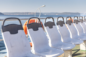 Fototapeta premium A beautiful row of plastic white chairs on the ferry on the sea