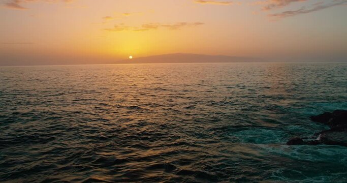 Solar disk near the horizont over island La Gomera and ocean. Sunset orange sky with light reflection on sea water in slow-motion.