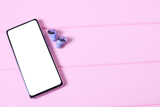 Mobile phone on pink table with headphones on table with cosmetics