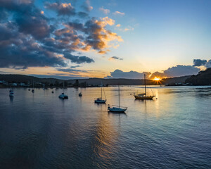 Sunrise over the water with clouds and boats