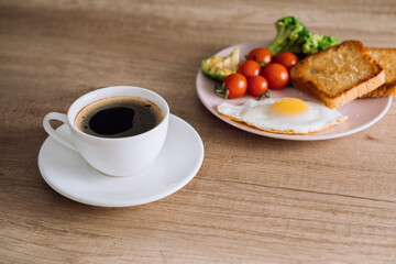 Cup of black coffee with homemade breakfast on the wooden table