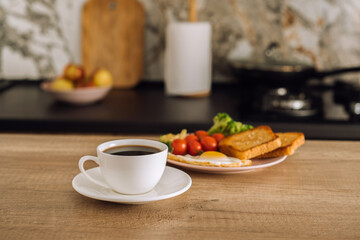 Cup of black coffee and breakfast in the background in the kitchen at home