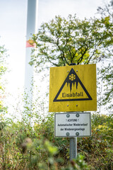 Close-up german yellow warning sign attention ice can fall down from the wind turbine, with wind turbine in background