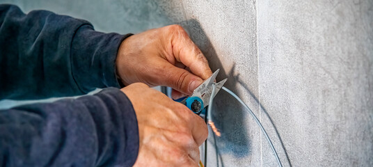 Electrician mounts an electrical outlet to the wall