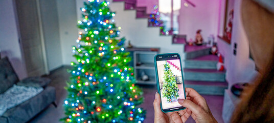 Beautiful woman using smart home app to decorate and lighting Christmas Tree. Back view