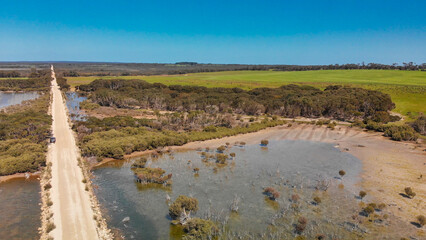Kangaroo Island unpaved road along lake and trees, aerial view from drone - Australia