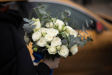 Bouquet of roses for bride. White flowers. Beautiful bouquet in hand of man.