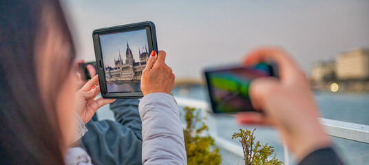 Naklejka premium Tourists taking pictures of Budapest Parliament at sunset, Hungary