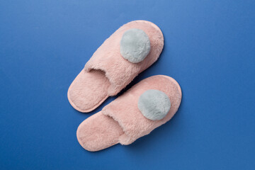 Soft pink slippers on color background, top view