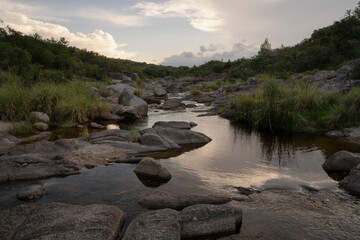 View of the river across the rocky hills at sunset. The sky reflection in the water surface.