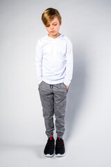 Young boy standing looking sad with hands in pockets