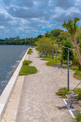Alice Wainwright Park, Miami, Florida- concrete path near the water with green plants along the...