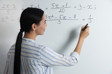 Young teacher explaining mathematics at whiteboard in classroom