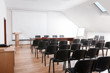 Empty conference room with projection screen, wooden table and many chairs