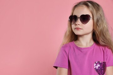 Obraz premium Girl wearing stylish sunglasses in shape of hearts on pink background. Space for text