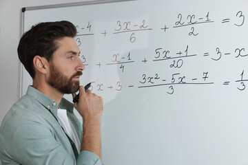Mature teacher at whiteboard in classroom during math lesson