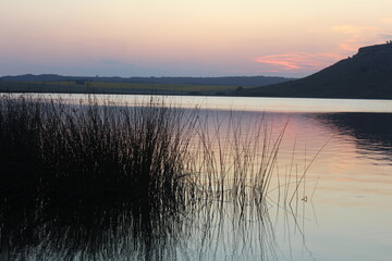 Atardecer en una hermosa laguna, junto a sierras y plantas