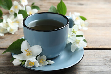 Cup of tea and fresh jasmine flowers on wooden table