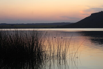 Atardecer en una hermosa laguna, junto a sierras y plantas