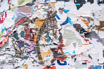 Naklejka premium Torn paper collage background on an old poster on a street wall. Texture and surface of torn paper.