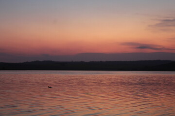 Atardecer en una hermosa laguna, junto a sierras y plantas