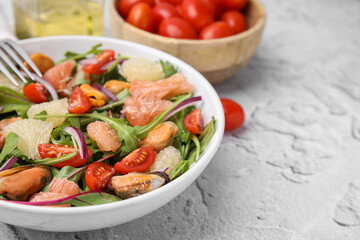 Delicious pomelo salad with tomatoes and mussels on white textured table, closeup. Space for text