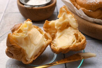 Delicious profiterole filled with cream on white tiled table, closeup