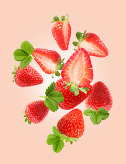 Delicious sweet strawberries and green leaves falling on pale pink background