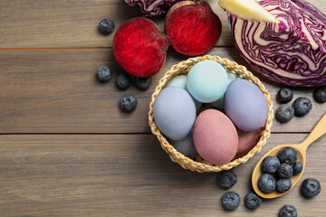 Fototapeta na wymiar Colorful Easter eggs painted with natural dyes and ingredients on wooden table, above view