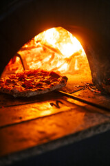 Pizza in the traditional pizza oven with a wood fire. Close up of hot cooking.