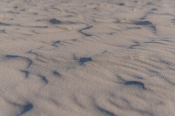 Sand on beach during the day in Destin, Florida as background. Selective focus of an untouched fine beach sand waves close-up view.