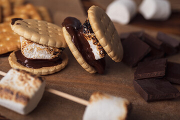 marshmallows, chocolate and cookies for making smore on brown background. view from above. copy...