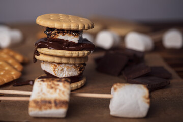 marshmallows, chocolate and cookies for making smore on brown background. view from above. copy space