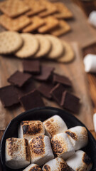 marshmallows, chocolate and cookies for making smore on brown background. view from above. copy space