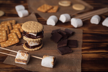marshmallows, chocolate and cookies for making smore on brown background. view from above. copy space