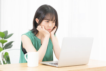 パソコンを見ながら悩んでいる若い女性