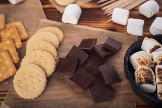 marshmallows, chocolate and cookies for making smore on brown background. view from above. copy space