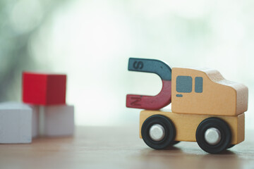 Horseshoe magnet on yellow car attracting red wood block.  U shape steel magnet