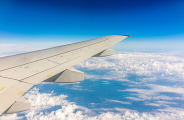 View from the airplane window at a beautiful cloudy sky and the airplane wing