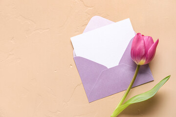 Envelope with blank card and tulip flower on color background