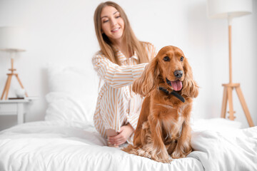 Young woman with red cocker spaniel sitting on bed at home