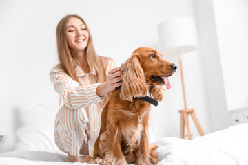 Young woman with red cocker spaniel sitting on bed at home