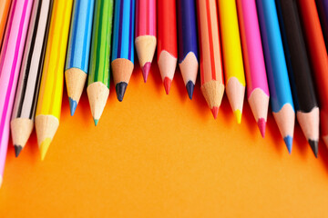 Set of colorful pencils on orange background, closeup