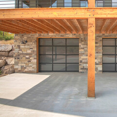 Square Two glass garage door of a modern custom house with stone veneer siding. Garage driveway...