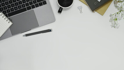 Office desk with laptop computer, coffee cup, notepad and pen. Flat lay, top view with copy space